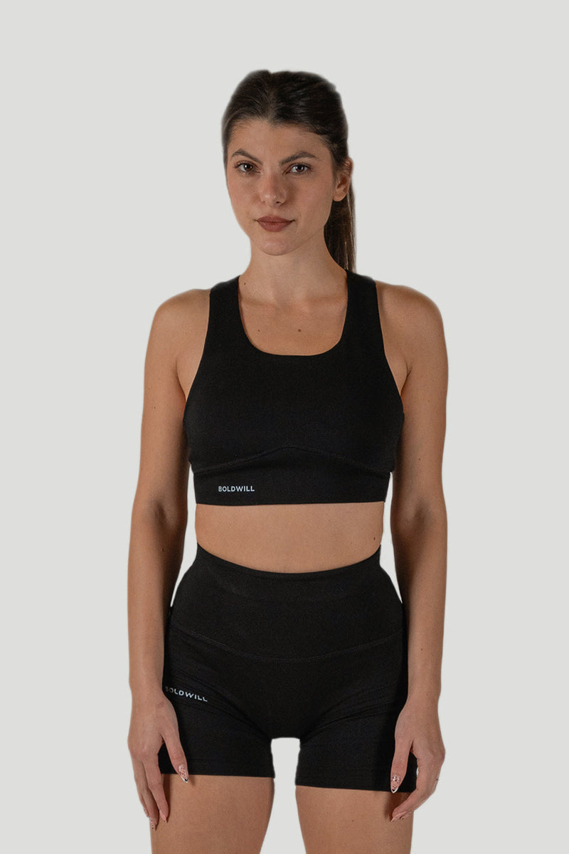 Woman wearing a black sustainable sports bra and biker shorts set